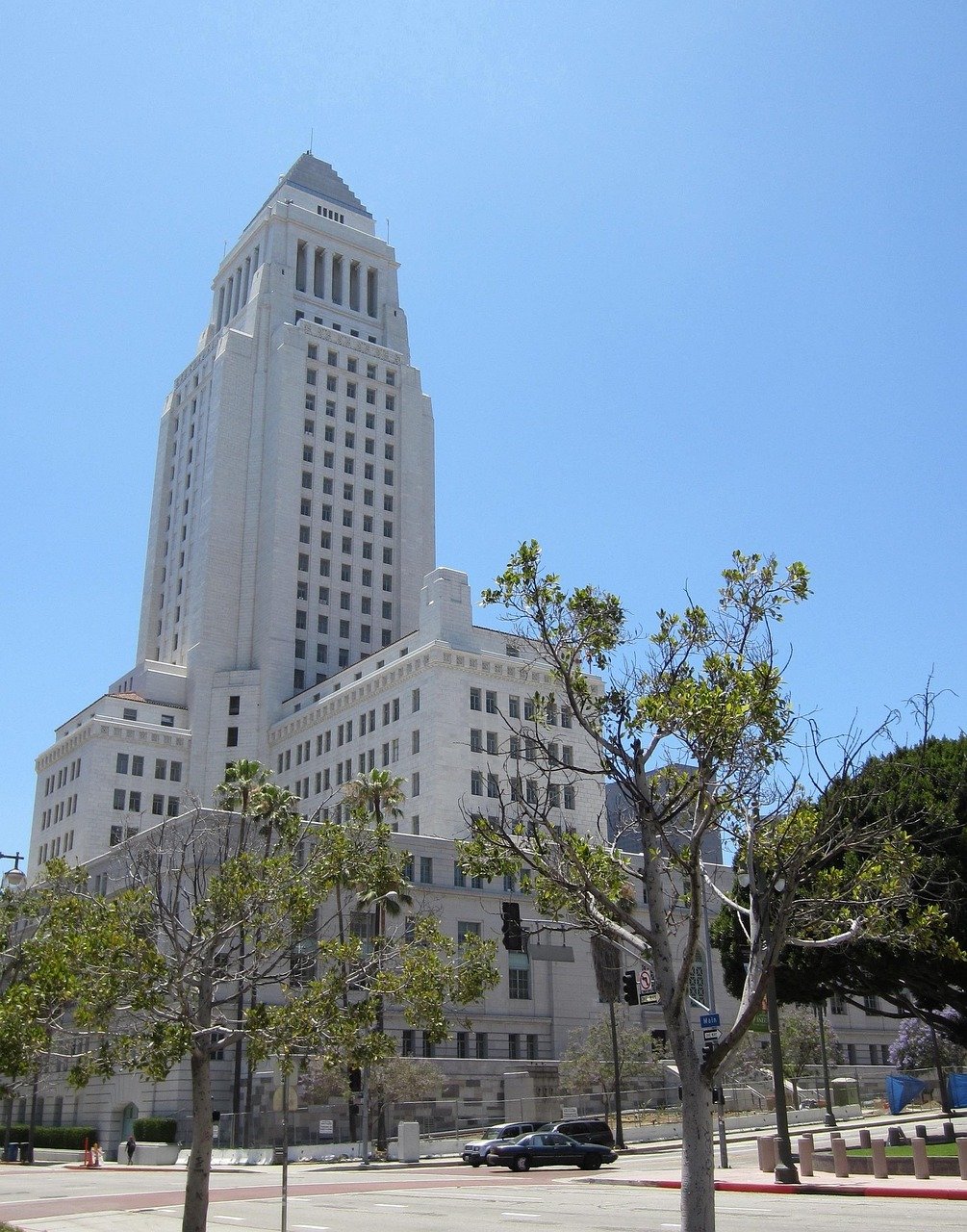 Los Angeles stadshusbyggnad med klarblå himmel och träd i förgrunden på en solig dag