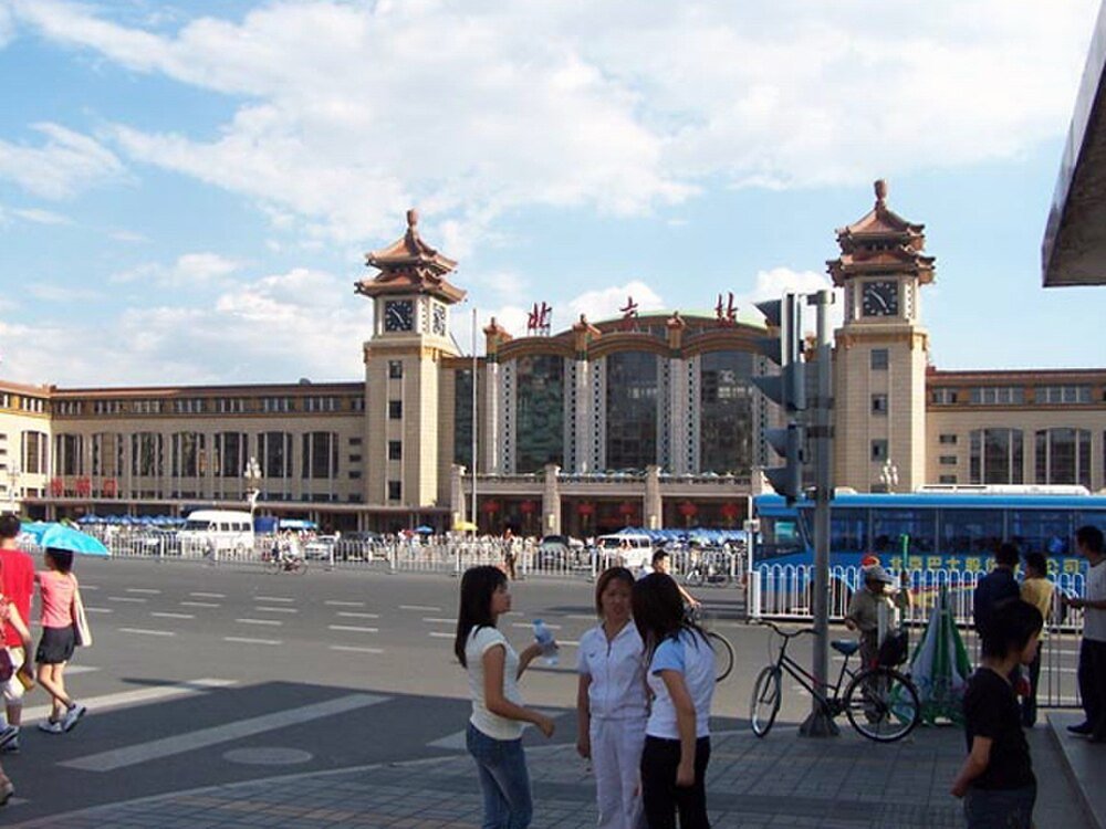 Beijing järnvägsstation exteriör med människor och bussar Beijing järnvägsstation med människor, bussar och cyklar på en solig dag i Kina