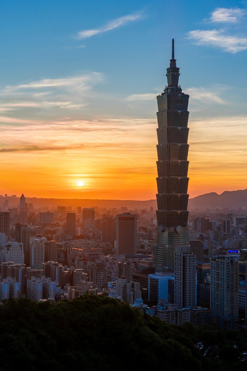 Taipei 101 skyskrapa som reser sig över Taipeis stadssilhuett under en livlig solnedgång med färgglad himmel och urbana byggnader