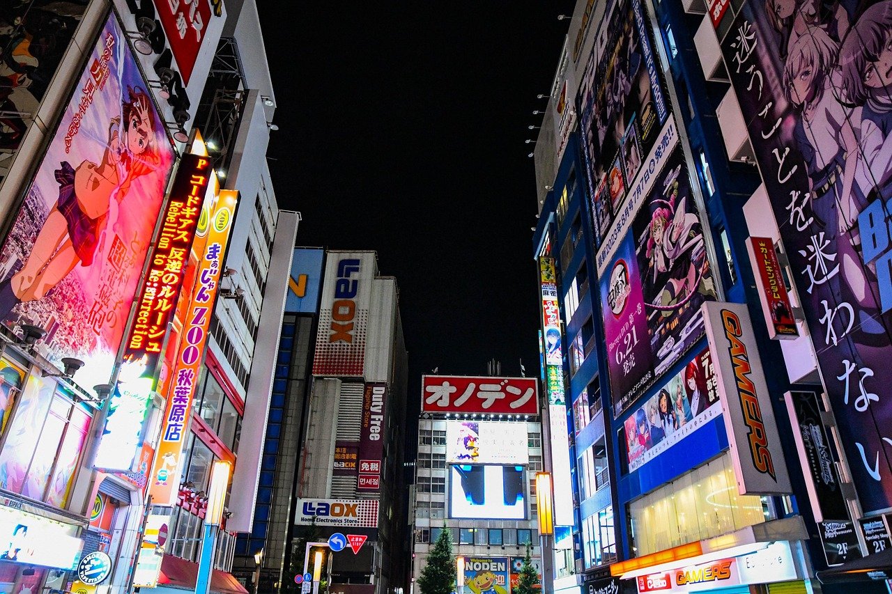 Nattvy av en livlig stadsgata i Japan med upplysta anime-skyltar och färgglada annonser