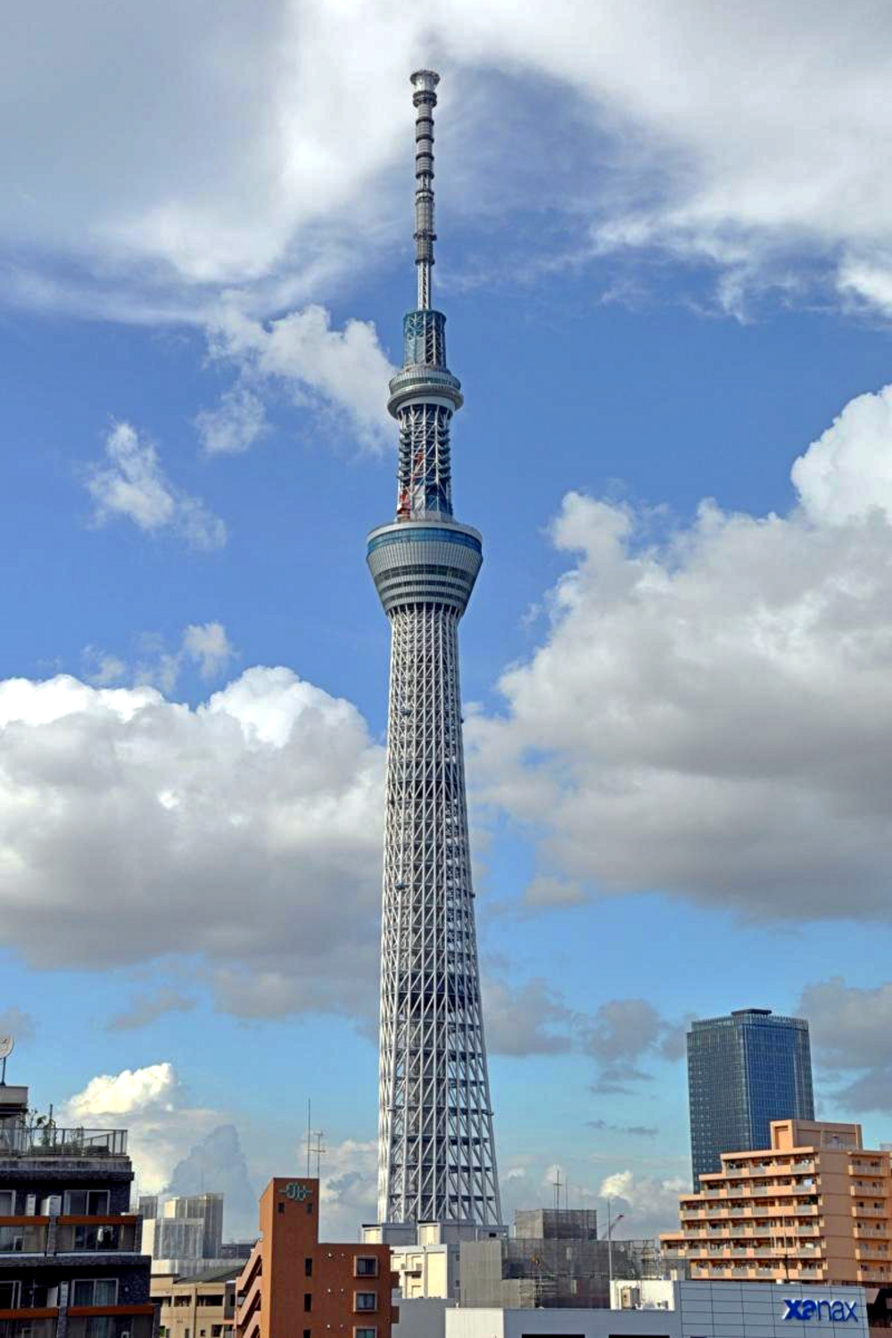 Tokyo Skytree som reser sig över stadens byggnader under en blå himmel med spridda moln i Tokyo, Japan