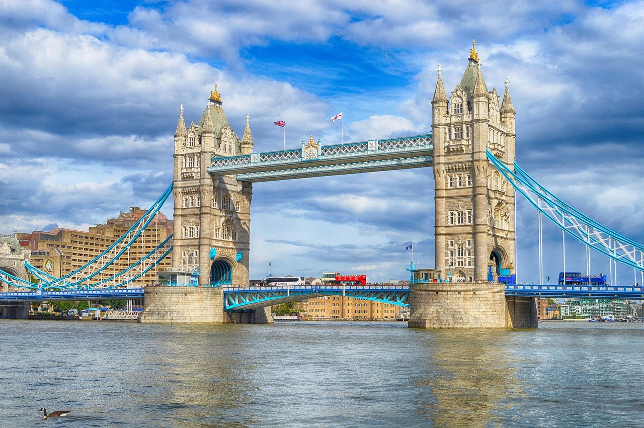Tower Bridge i London över Themsen med blå himmel och passerande röd dubbeldäckare