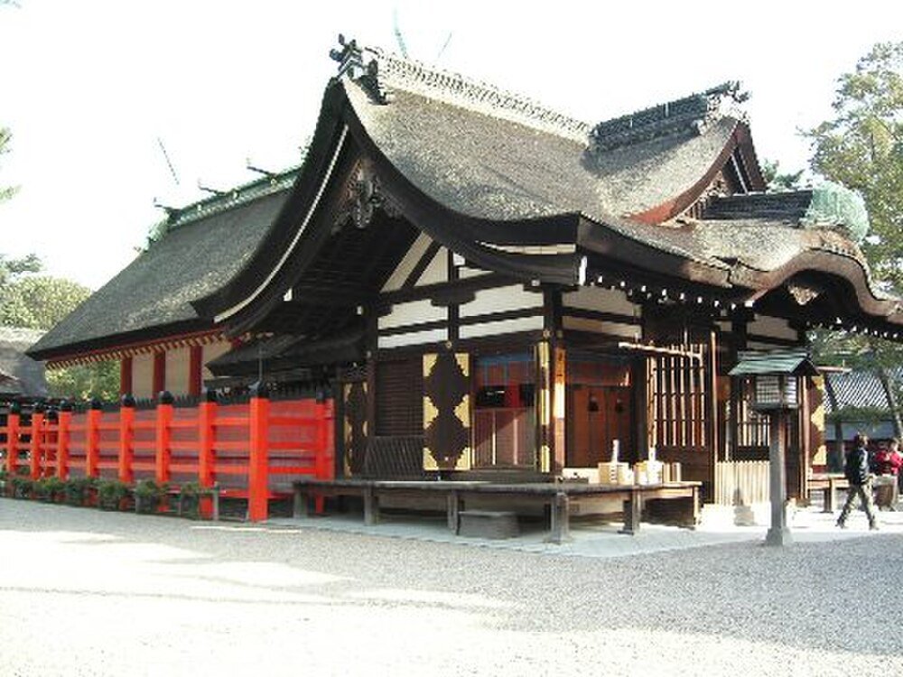Traditionell japansk helgedom med halmtak Traditionell japansk helgedom med välvt halmtak och livfullt rött trästaket i en fridfull utomhusmiljö