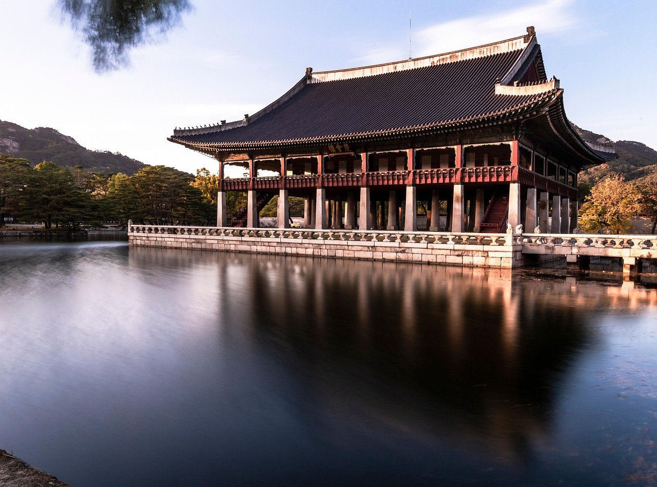 Traditionell koreansk paviljong Gyeonghoeru omgiven av vatten och träd med berg i bakgrunden