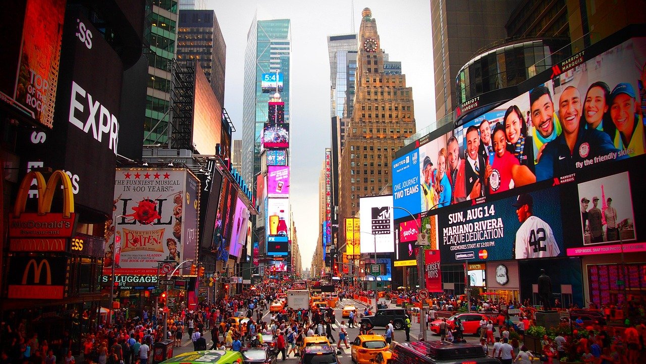 Livliga Times Square i New York City med folkmassor, gula taxibilar och livfulla digitala skyltar som annonserar varumärken och evenemang