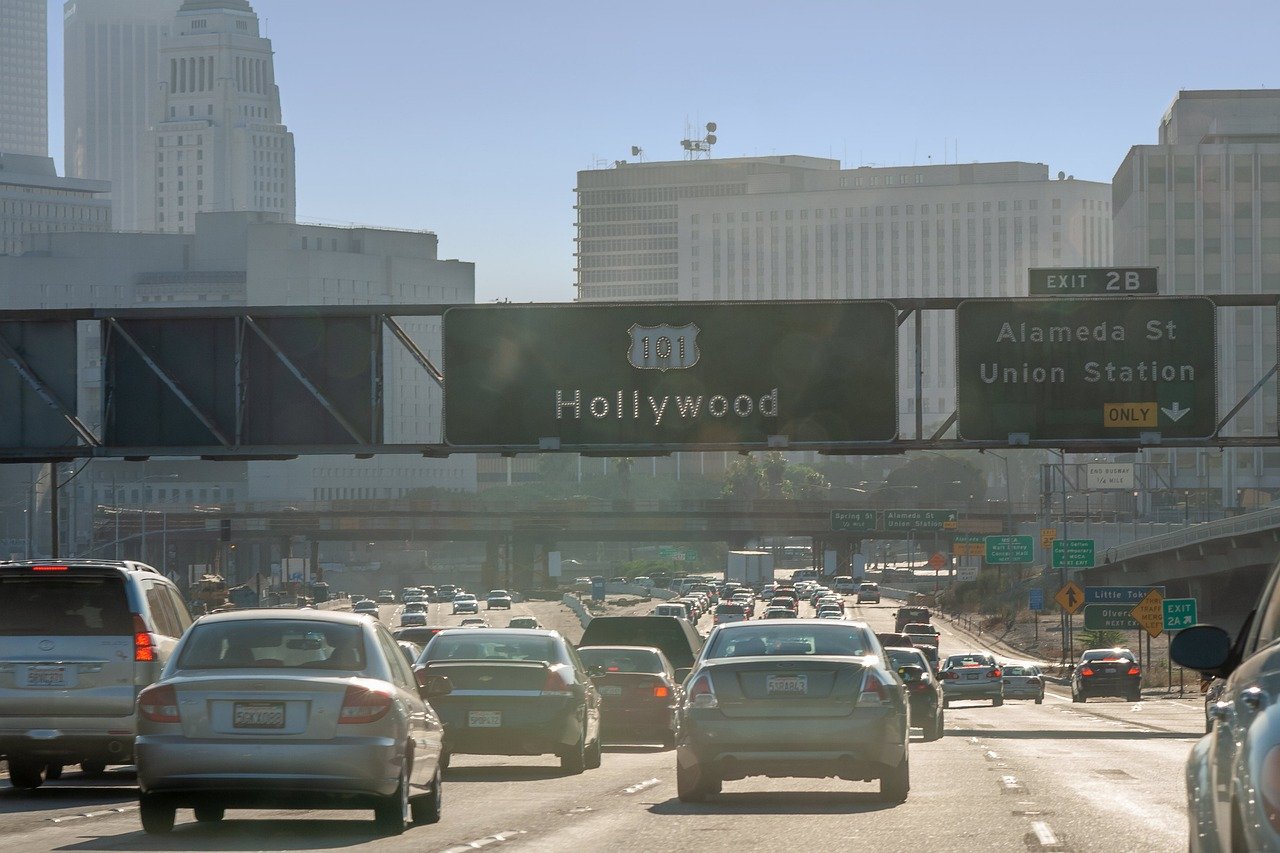 Trafikerad motorväg på US Route 101 mot Hollywood med stadsbyggnader och avfartsskyltar i Los Angeles