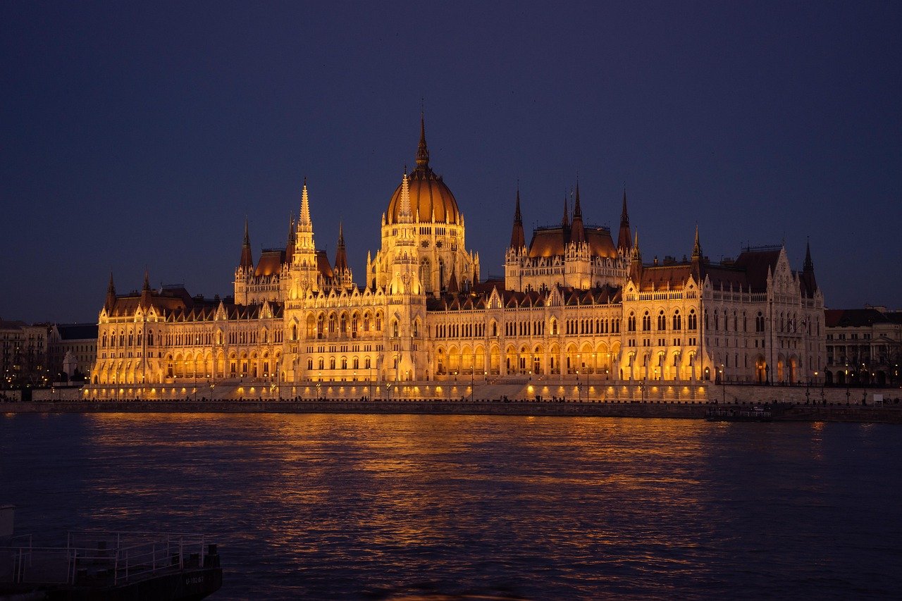 Upplyst ungersk parlamentsbyggnad på natten som speglas i Donau i Budapest, Ungern