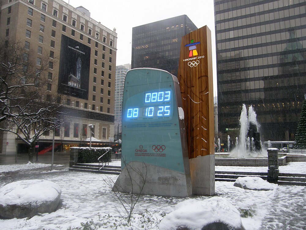 Nedräkningsklocka för Vancouver 2010 vinter-OS Nedräkningsklocka för Vancouver 2010 vinter-OS i snöig urban plaza med omgivande byggnader och fontän