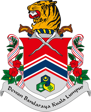 Vapen för Dewan Bandaraya Kuala Lumpur med ett tigerhuvud, korsade kris och blommiga dekorationer med band