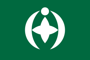 Grön flagga med vitt stjärn- och halvmåneemblem Grön flagga med ett vitt cirkulärt emblem med en stjärnform och halvmåne-liknande kurvor som symboliserar enhet och harmoni