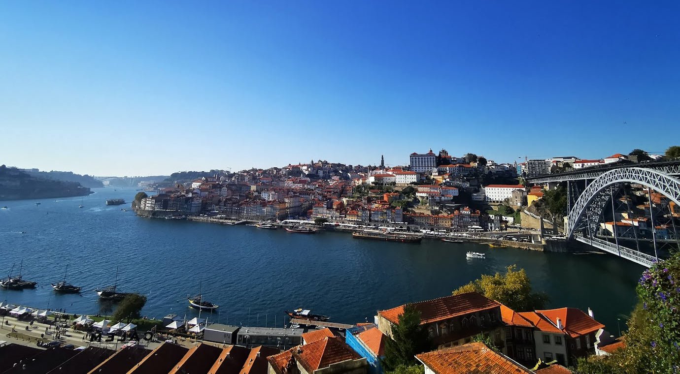 Porto stadsbild med Dourofloden och Dom Luís I-bron Scenisk vy över Porto stad med Dourofloden, historiska byggnader och Dom Luís I-bron under klarblå himmel