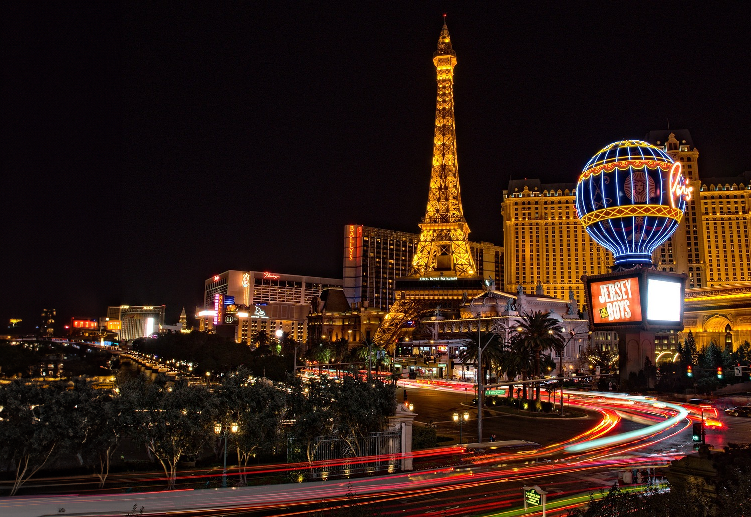 Las Vegas Strip på natten med Eiffeltorn-replika Nattvy av Las Vegas Strip med upplyst Eiffeltorn-replika och livfulla neonskyltar som visar kasinon och underhållning.