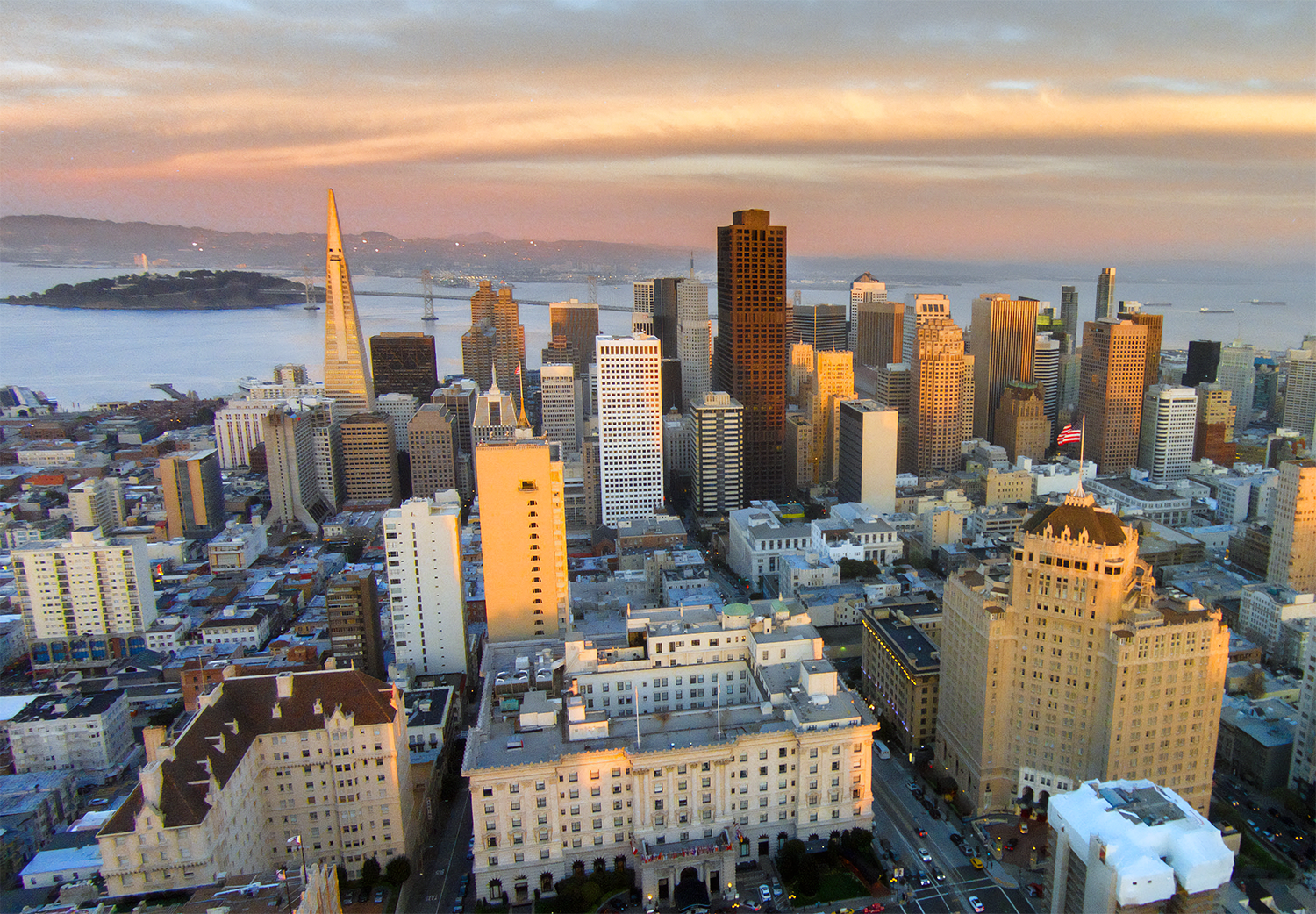 San Franciscos skyline med Transamerica Pyramid vid solnedgången Flygfoto av San Franciscos skyline vid solnedgången med den ikoniska Transamerica Pyramid och Bay Bridge i bakgrunden