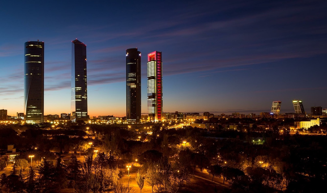 Madrid Cuatro Torres Affärsdistrikt på Natten Nattens silhuett av Madrid med upplyst Cuatro Torres affärsdistrikt och moderna skyskrapor i skymningen