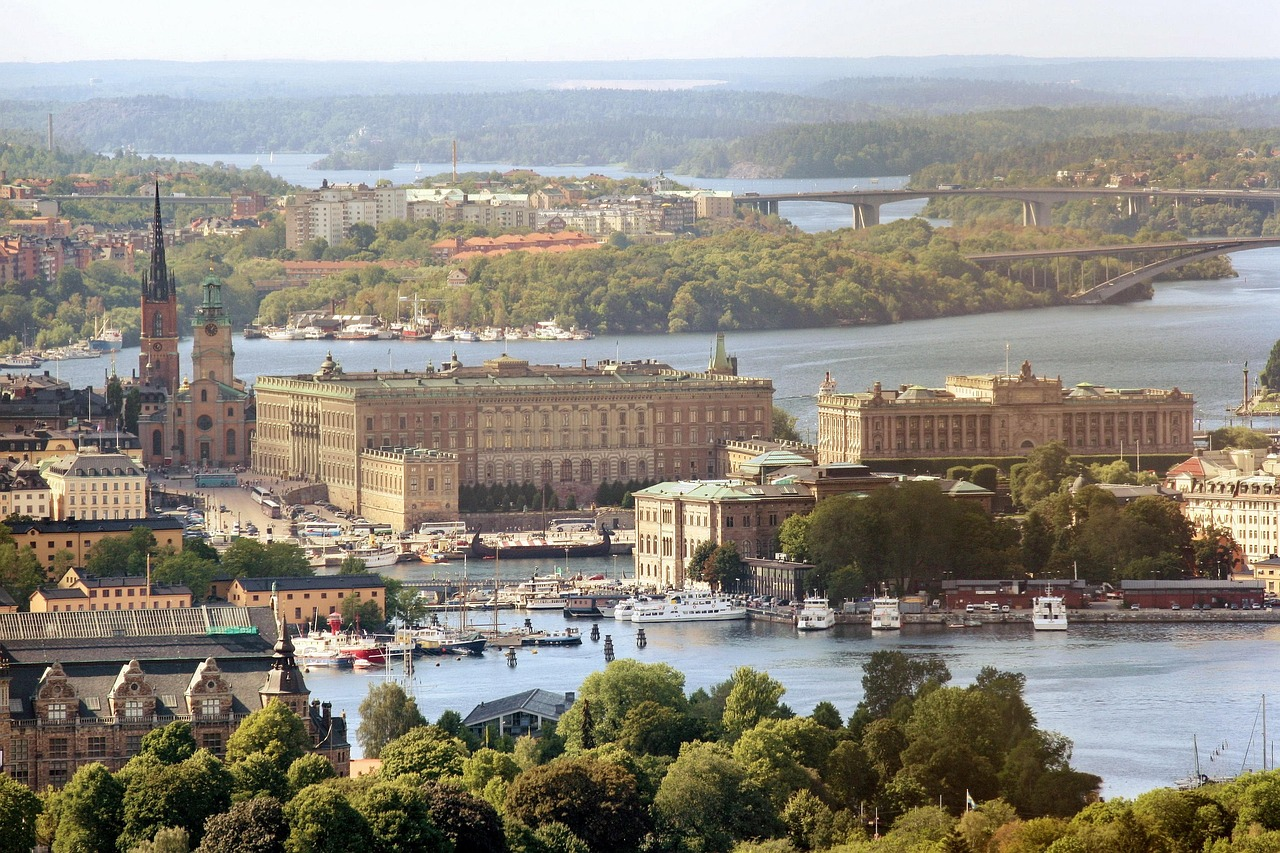 Stockholms stadsbild med vattenfront och historiska byggnader Scenisk vy över Stockholm med historiska byggnader, vattenfront, båtar och frodig grönska under klar himmel
