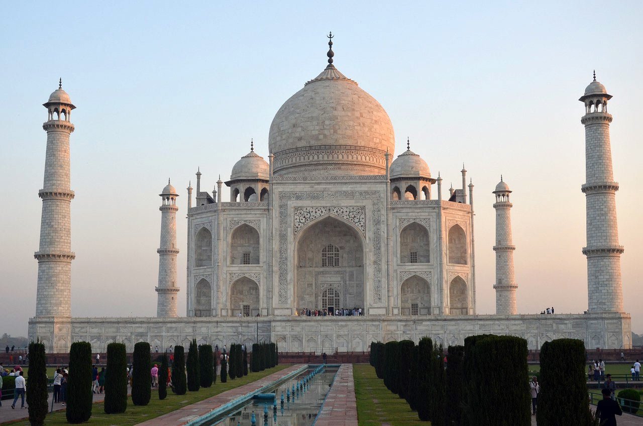 Taj Mahal Vit Marmormonument vid Solnedgången Taj Mahal i Indien vid solnedgången med sin ikoniska vita marmorkupol och minareter, omgiven av trädgårdar och spegeldamm