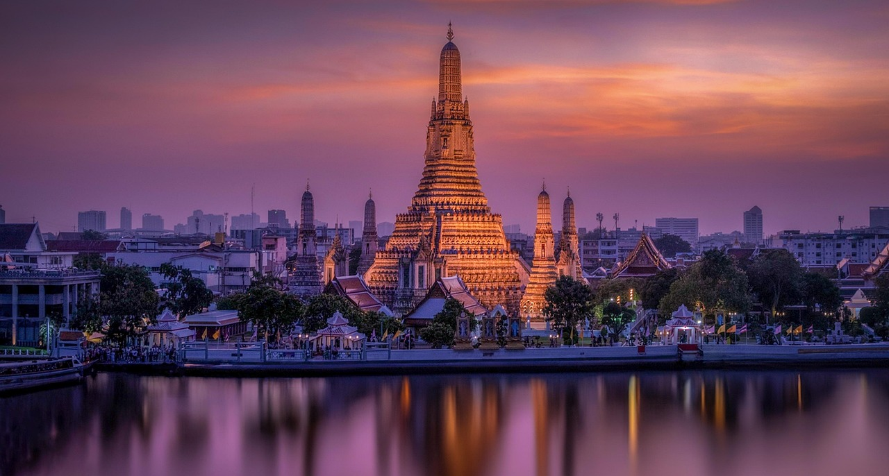 Wat Arun-templet solnedgångsreflektion Bangkok Wat Arun-templet vid solnedgången med en livfull lila och orange himmel som speglas på floden i Bangkok, Thailand