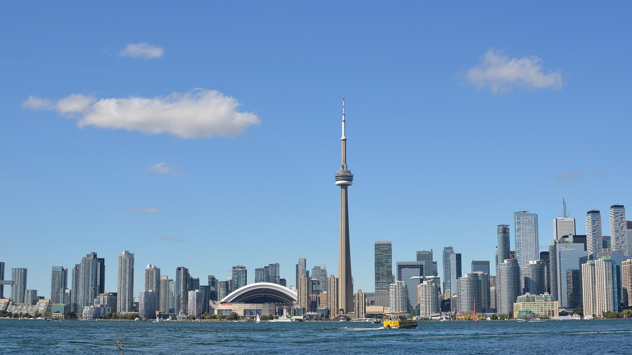 Torontos silhuett med CN Tower och strandlinje Torontos stadssilhuett med CN Tower och strandlinje på en klar solig dag med blå himmel och spridda moln