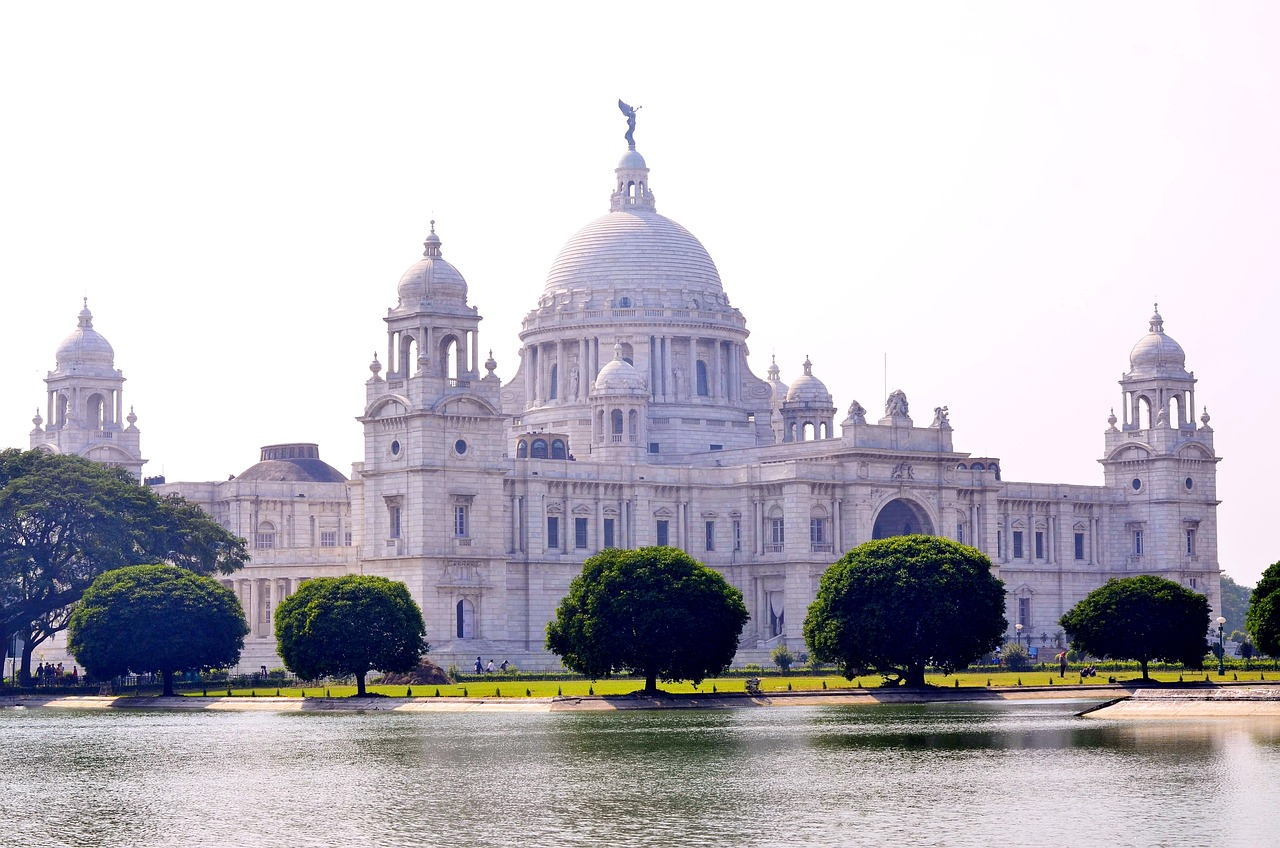 Victoria Memorial Kolkata vit marmormonument Victoria Memorial Kolkata majestätisk vit marmorsbyggnad med kupoler och statyer nära vattendrag och gröna träd