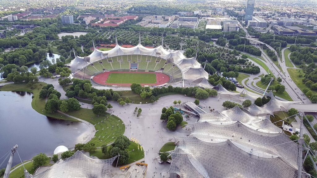 Flygfoto av Münchens Olympiapark och Olympiastadion med tälttak och Olympiaturm i bakgrunden