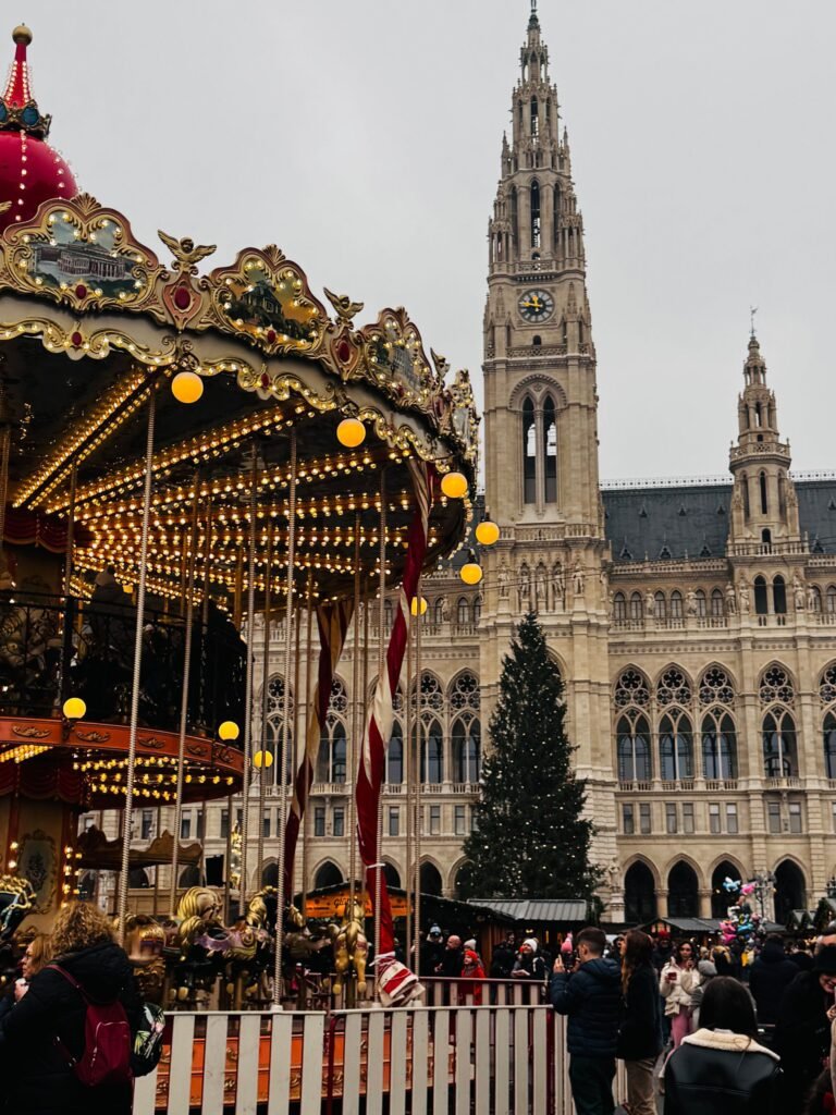 Wiens Christkindlmarkt vid Rathaus, med en upplyst karusell och julgran framför det gotiska rådhuset