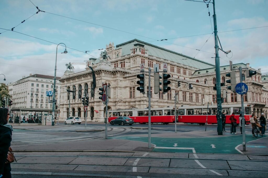 Wiener Staatsoper-byggnaden med en passerande röd spårvagn, historiskt och modernt vävt samman