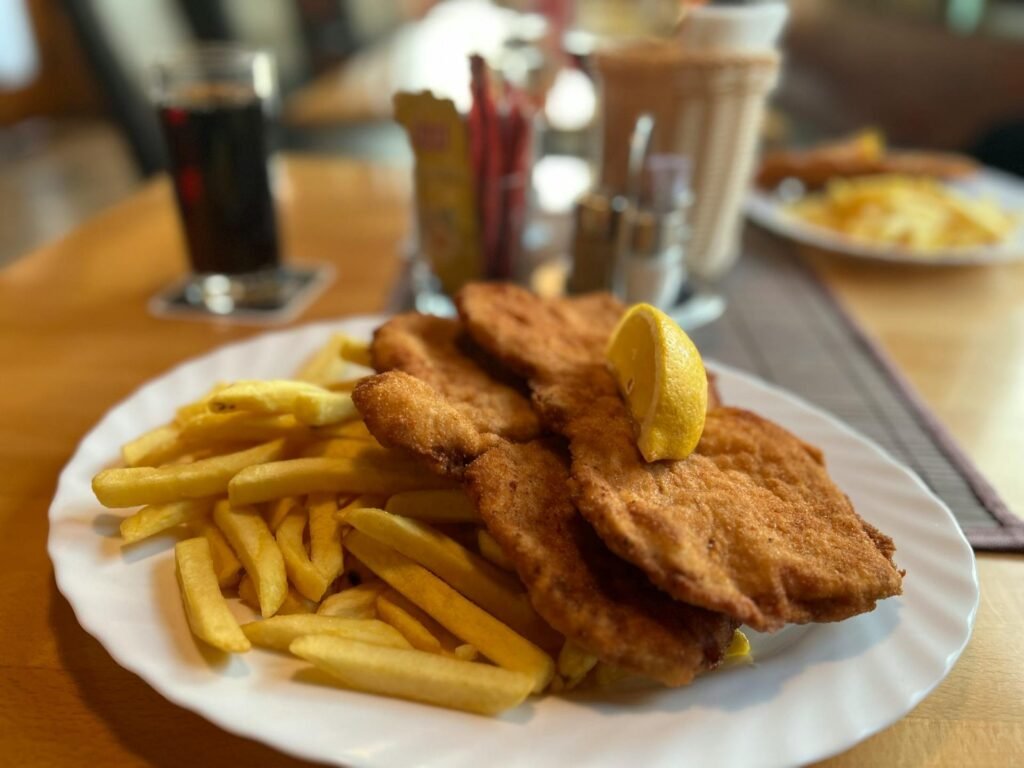 En traditionell Wiener Schnitzel serverad med pommes och citron på en mysig restaurang i Wien